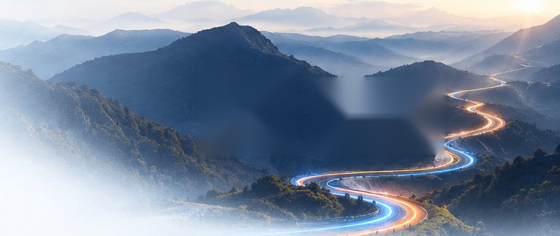 A lit route curving toward a city at dusk